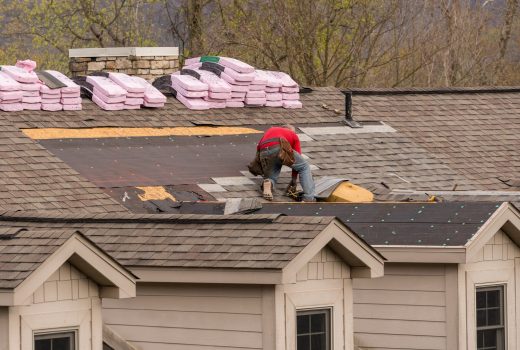 Roofing contractor removing the old tiles before replacing with new shingles on a townhouse roof